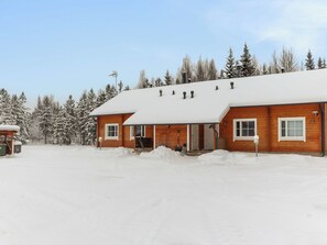 A wooden cabin with a snow-covered roof and a front porch.