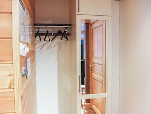 Interior de madera con un perchero, una puerta que da a otra habitación y un termostato instalado en la pared.
