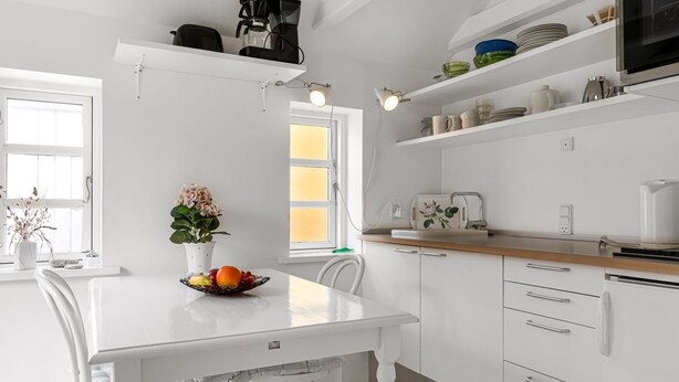 Een moderne keuken met witte kastjes, een eettafel en een koffieapparaat.