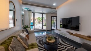 A modern living room with a sofa, coffee table, and TV. - Villa by Olive - Nerul (Nerul)