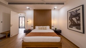A modern bedroom with a wooden bed, bedside tables, a ceiling fan, and a large framed artwork on the wall. - Villa by Olive - Nerul (Nerul)