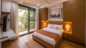 A modern hotel room with a large bed, a TV, a balcony with a view of greenery, and a ceiling fan. - Villa by Olive - Nerul (Nerul)