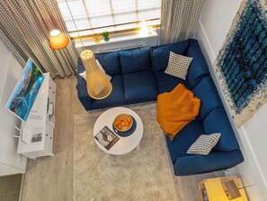 En moderne stue med en blå sofa, et rundt sofabord og en dekorativ lampe.