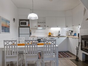 Een moderne keuken met witte kasten, een magnetron, een fornuis en een koffieapparaat.