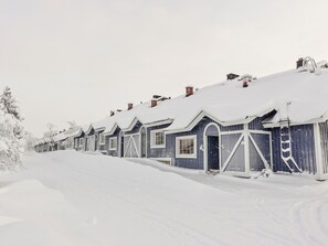 Eine Reihe von schneebedeckten Holzhäusern mit großen Fenstern und Türen, wahrscheinlich ein Hotel oder Resort.
