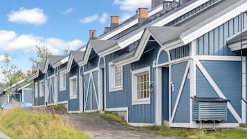 A row of blue houses with white trim and grey roofs, arranged in a linear fashion along a gravel path.