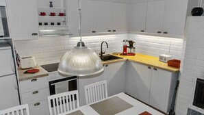 A compact kitchen with white cabinetry, a built-in microwave, a coffee maker, and a hanging pendant light. - Päivänsäde by Interhome (Inari)