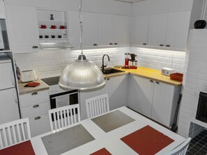 A compact kitchen with white cabinetry, a built-in microwave, a coffee maker, and a hanging pendant light.