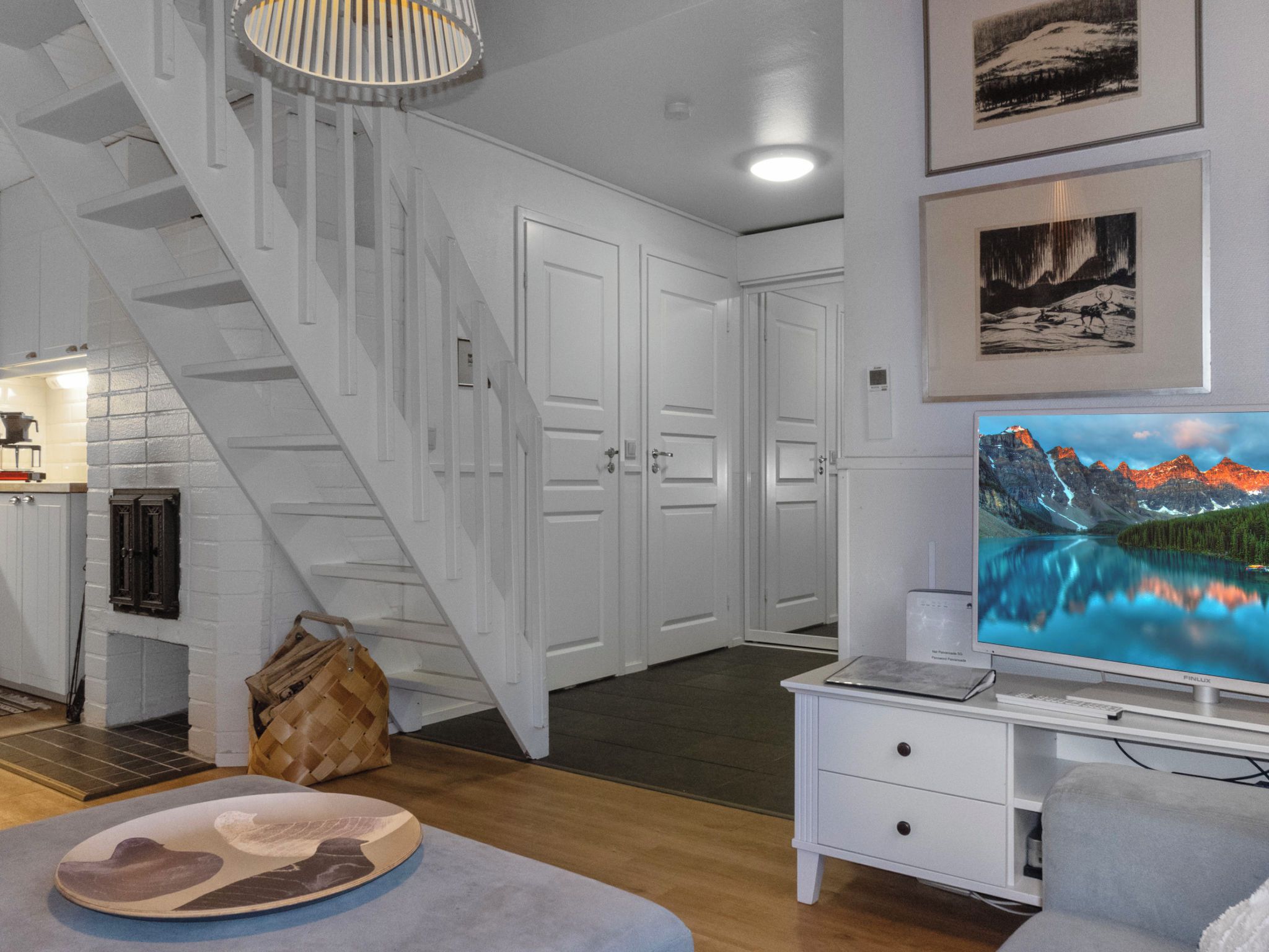 Een moderne woonkamer met een trap, een open haard, een televisie en kunstwerken aan de muur.