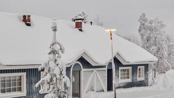 A snow-covered house with a chimney, a door, and a window.