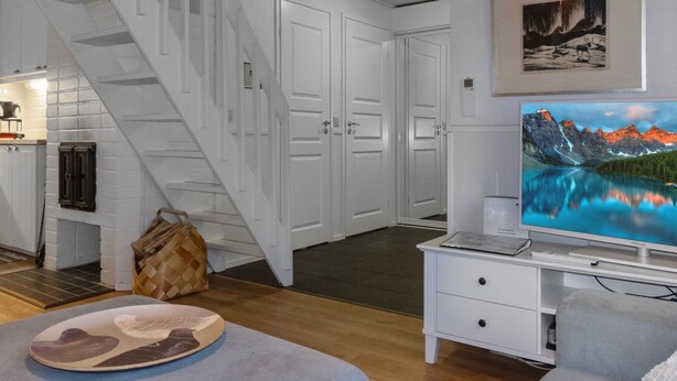 A modern living room with a staircase, a fireplace, and a television on a white stand. - Päivänsäde by Interhome (Inari)
