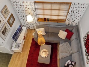 Un espace de vie compact avec un canapé gris, un tapis rouge et un plancher en bois.