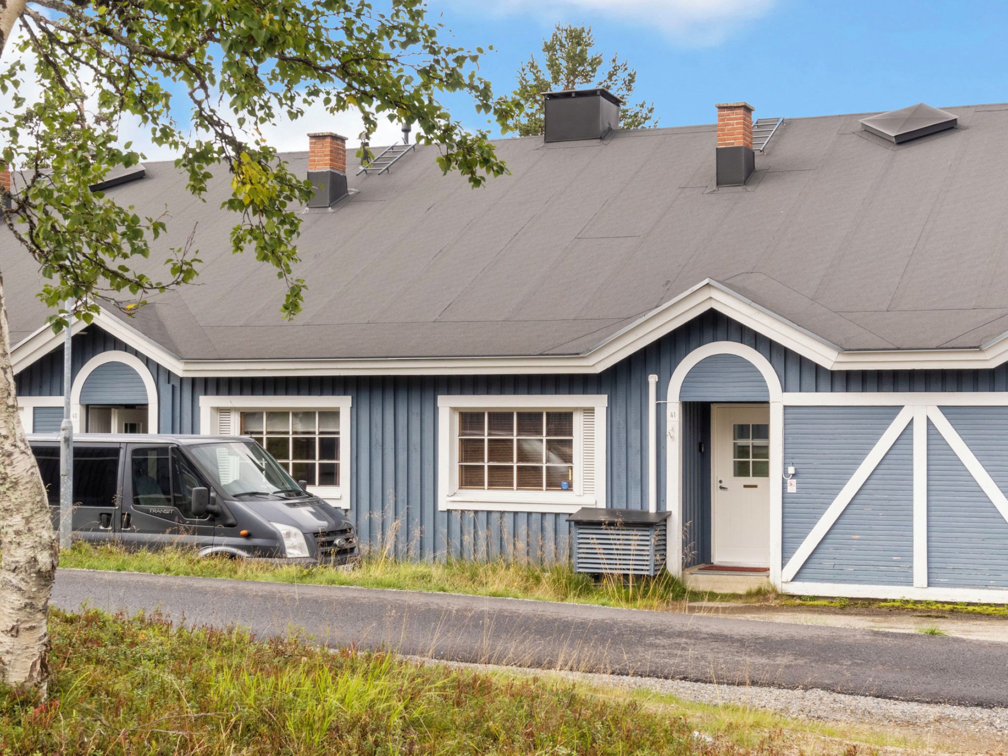 Un immeuble résidentiel avec un garage, un véhicule de transport stationné et un ciel dégagé.