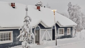 A snow-covered house with a chimney, a porch, and a street lamp. - Päivänsäde by Interhome (Inari)