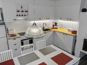 A compact kitchen with white cabinetry, a hanging pendant light, a coffee maker, and a toaster.