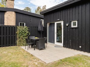 A patio area with a table and chairs, a black fence, and a door with a glass panel.