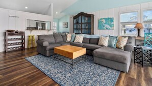 A modern living room with a sectional sofa, wooden coffee table, and patterned rug. - Hideaway at Redhead Road by Miss Kitty’s (Rockport)