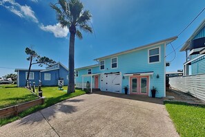 A two-story residential building with a front garage, a small porch, and a well-maintained lawn. - Hideaway at Redhead Road by Miss Kitty’s (Rockport)