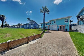 A residential area with a pathway leading to a house with a red door and a blue exterior. - Hideaway at Redhead Road by Miss Kitty’s (Rockport)