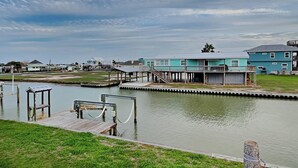 A waterfront property with a dock, a covered area, and a building with a blue exterior. - Hideaway at Redhead Road by Miss Kitty’s (Rockport)