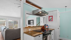 A modern kitchen with white cabinetry, a built-in oven, and a countertop with a range hood. - Hideaway at Redhead Road by Miss Kitty’s (Rockport)