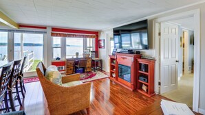 A spacious living room with a large TV, a fireplace, and a view of the outdoors. - Oak Bay Beach House in Port Hadlock (Port Hadlock-Irondale)