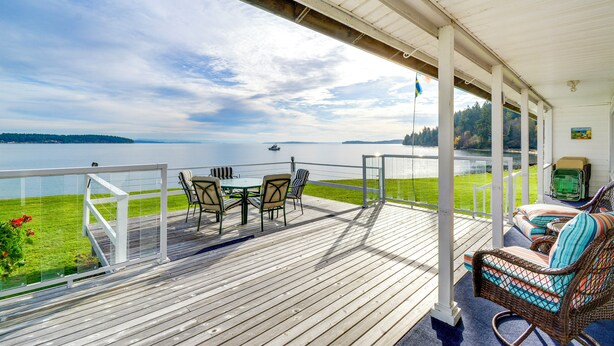 A wooden deck with a table and chairs, overlooking a lake. - Oak Bay Beach House in Port Hadlock (Port Hadlock-Irondale)