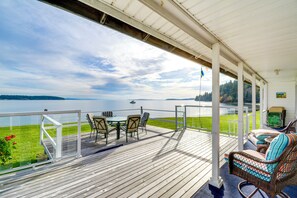Een houten terras met een tafel en stoelen, met uitzicht op een meer.