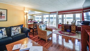 A spacious living room with a sofa, chairs, a coffee table, and a view of a lake through large windows. - Oak Bay Beach House in Port Hadlock (Port Hadlock-Irondale)