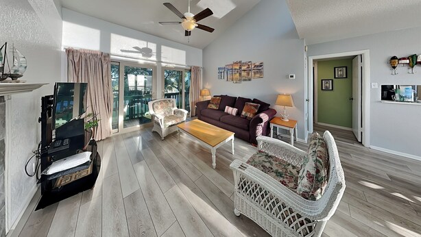 A spacious living room with a sofa, two chairs, a coffee table, and a television. - A Bay From It All by Miss Kitty’s (Rockport)