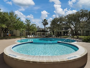 A swimming pool with a 'No Diving' sign, surrounded by lounge chairs and trees.