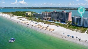 A beachfront hotel with multiple buildings, a sandy beach, and a clear blue sky. - Estero Island Beach Villas by Distinctive Beach Rentals (Fort Myers Beach)