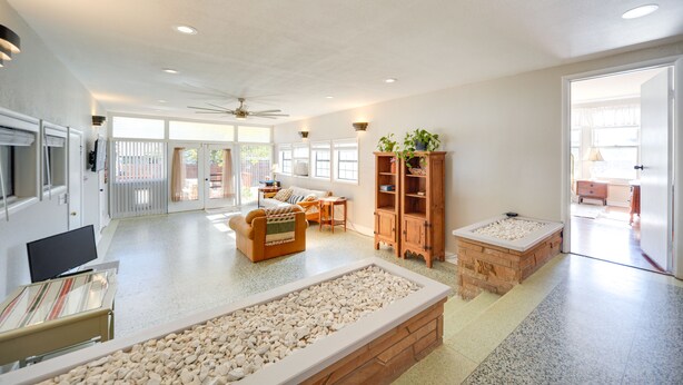 A spacious living area with a large TV, seating, a wooden cabinet, and a pebbled floor. - Pet-Friendly Brady Vacation Home Near Wineries! (Brady)