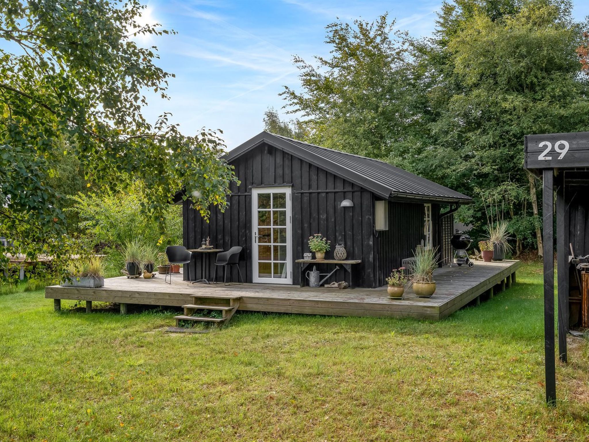 A wooden cabin with a porch, a table with chairs, and potted plants.