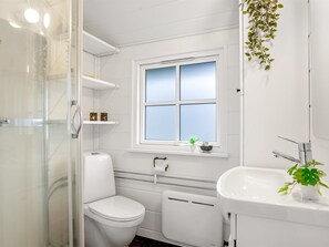 A bathroom with a toilet, a sink, a shower, and a window. - "Imma" -  from the sea by Interhome (Hals)
