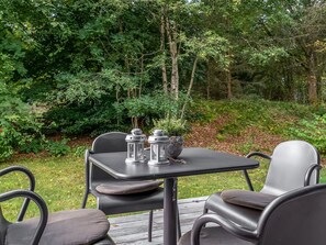 Un espace extérieur aménagé avec une table et des chaises, entouré de verdure.