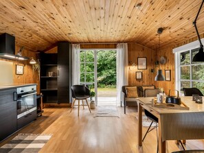 Une cuisine moderne dotée d’un four encastré et d’un coin repas avec une table et des chaises en bois.