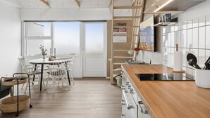 A modern kitchen with a wooden countertop, white cabinets, and a dining area with a table and chairs.
