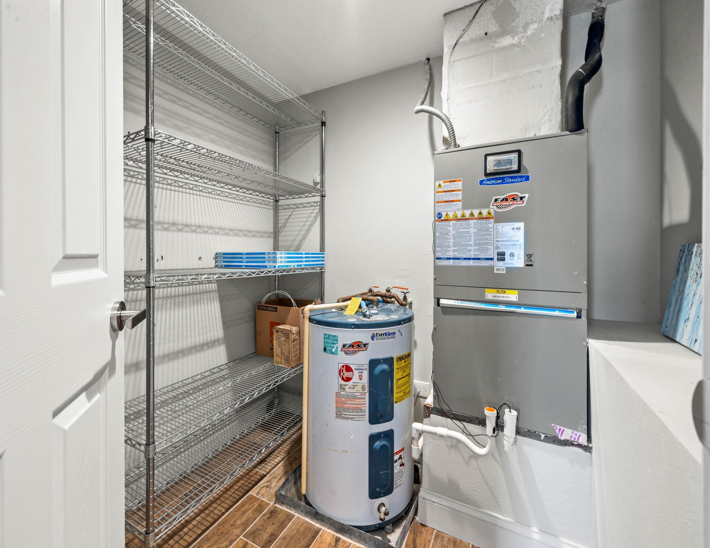 Un cuarto de servicio pequeño y funcional con calentador de agua, estanterías y una puerta.