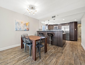 Een moderne keuken met donkerhouten kasten, roestvrijstalen apparatuur en een centraal eiland met barstoelen.