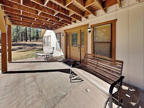 A covered porch with a wooden bench, a table, and a door with stained glass windows. - Quiet Mountain Hideaway by Ruidoso Vacation Rentals (Ruidoso)
