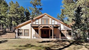 A two-story cabin with a front porch, large windows, and a covered entryway. - Quiet Mountain Hideaway by Ruidoso Vacation Rentals (Ruidoso)