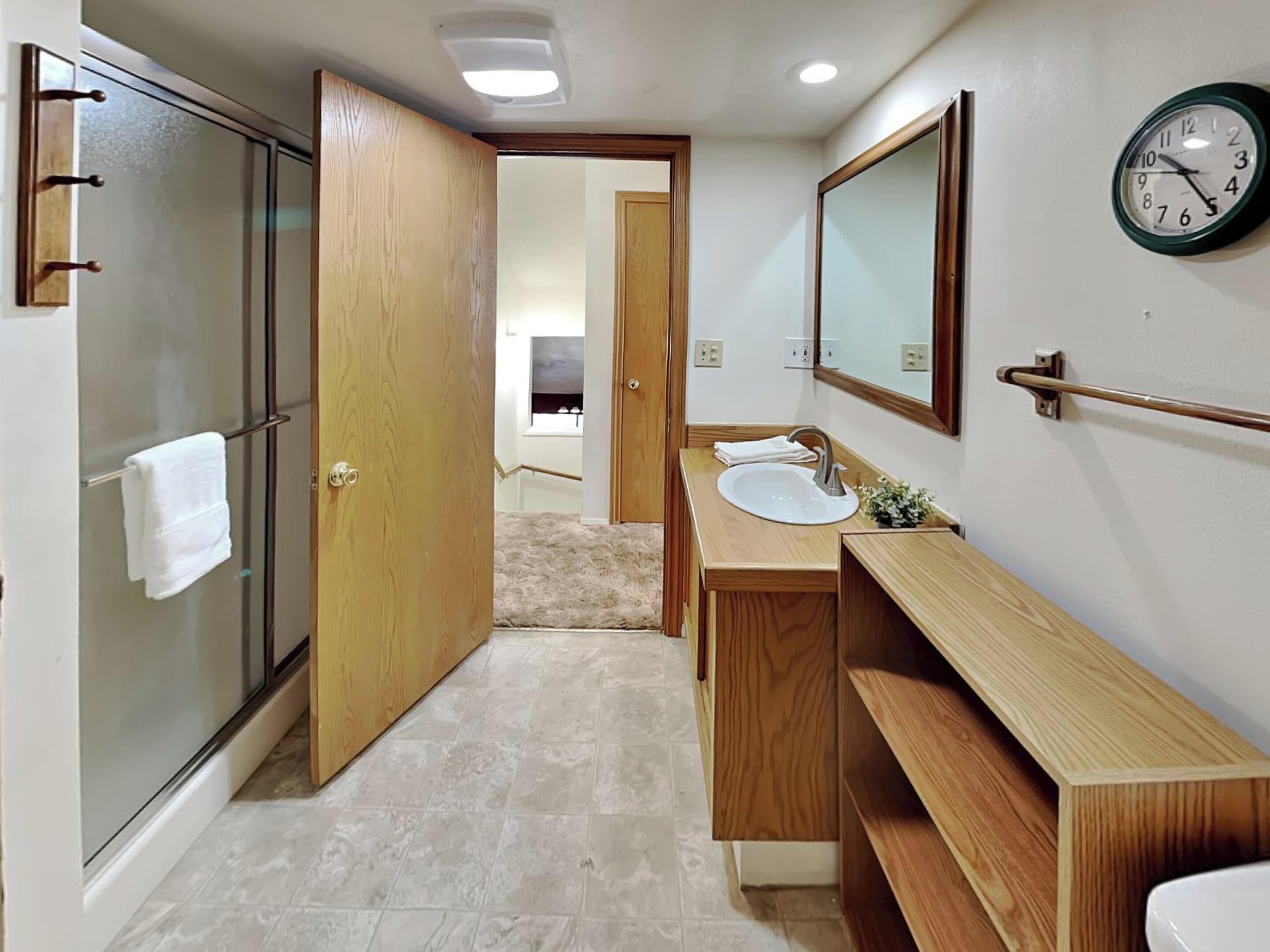 A modern bathroom with a glass shower, wooden vanity, and a mirror above the sink.