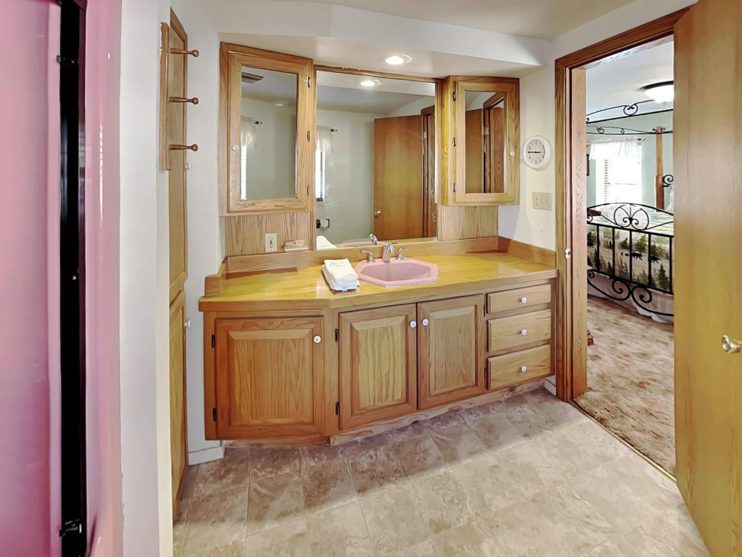 A bathroom with wooden cabinets, a sink, and a mirror.
