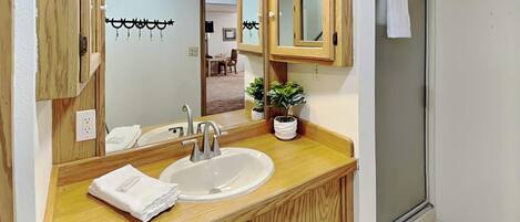 Un baño con tocador de madera, un lavabo, un espejo y una planta en maceta.