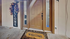 A wooden door with a glass panel, a welcome sign, and a doormat. - Quiet Mountain Hideaway by Ruidoso Vacation Rentals (Ruidoso)