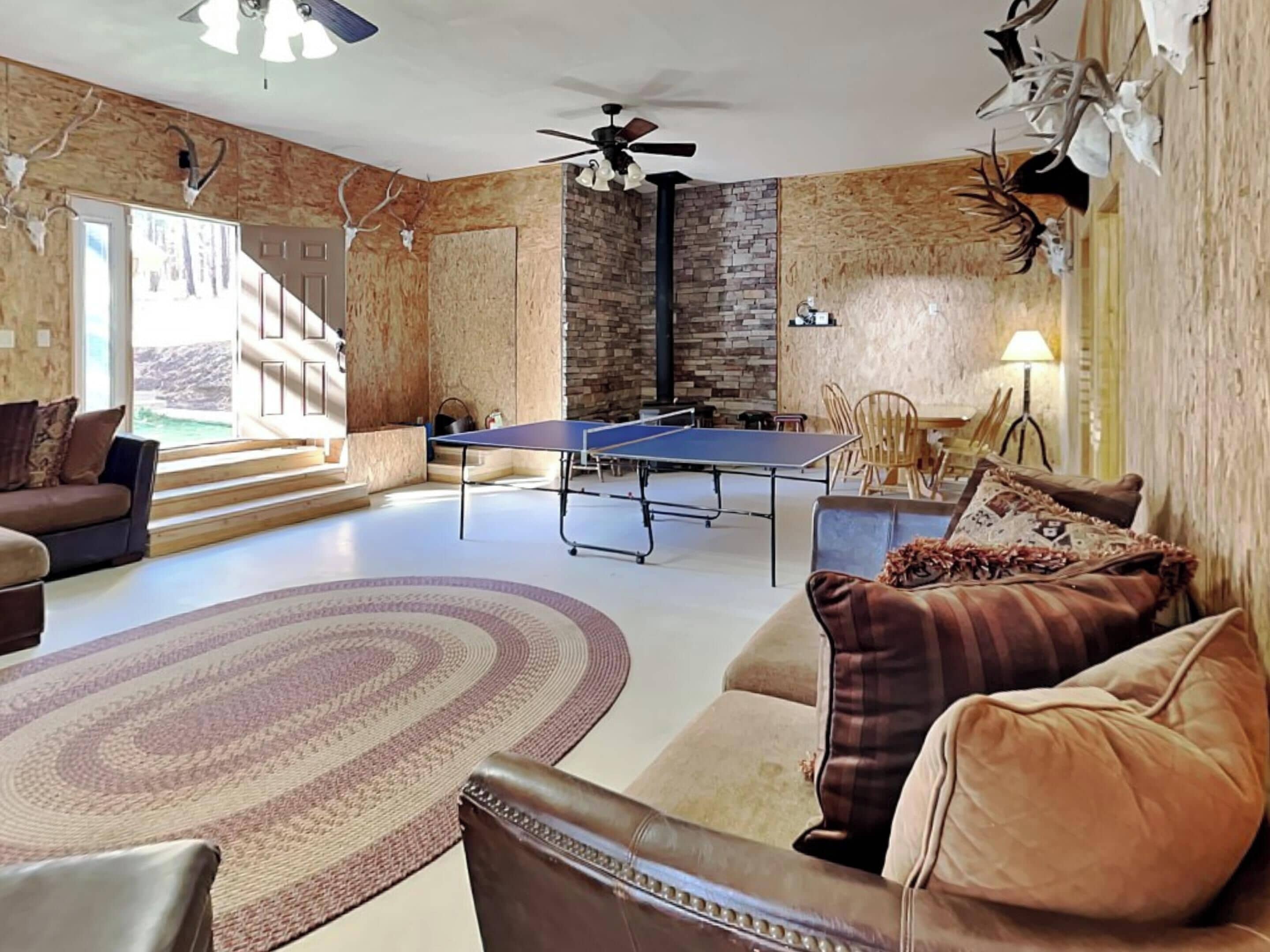 Una sala de estar con mesa de ping pong, sofá, mesa de centro y chimenea.