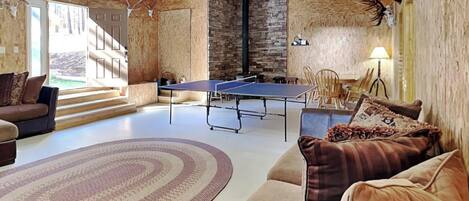 A living room with a ping pong table, a sofa, a coffee table, and a fireplace.