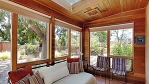 A cozy room with a large bed, two chairs, and a window overlooking a garden. - Casa Amarilla by Kokopelli Property Management (Santa Fe)