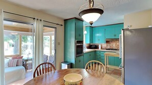 A kitchen with teal cabinets, a wooden dining table, and a refrigerator. - Casa Amarilla by Kokopelli Property Management (Santa Fe)